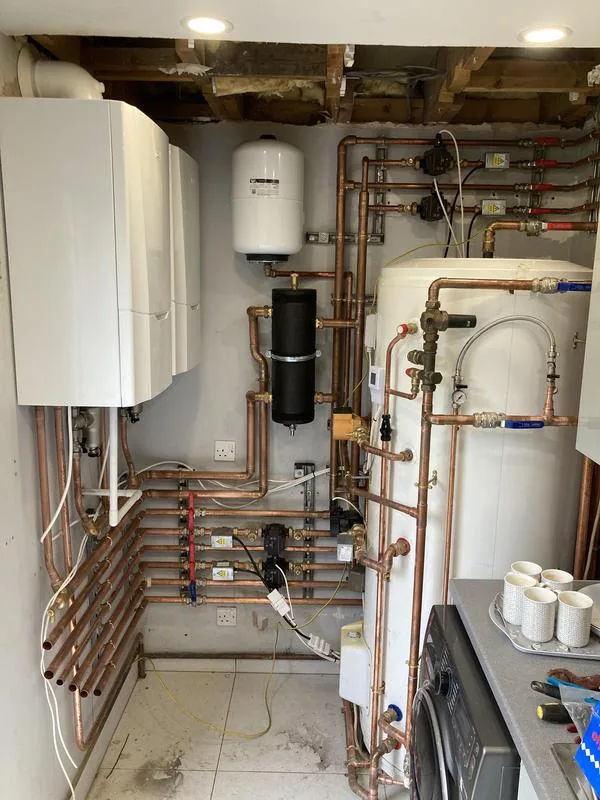 Boiler, unvented cylinder and neatly run copper pipework in a plant room