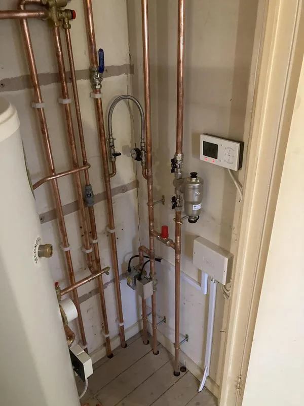 Close-up of vertical copper pipe runs and heating controls