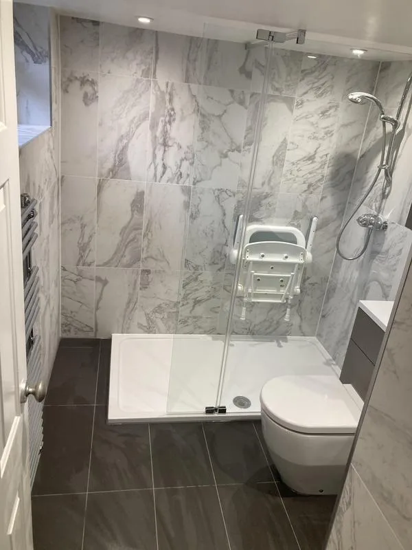 Accessible wet room with low-profile shower tray, fold-down seat and grey tiling