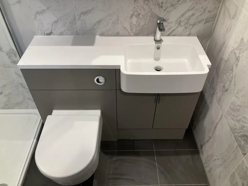 Close-up of basin and concealed cistern unit with marble-effect tiles