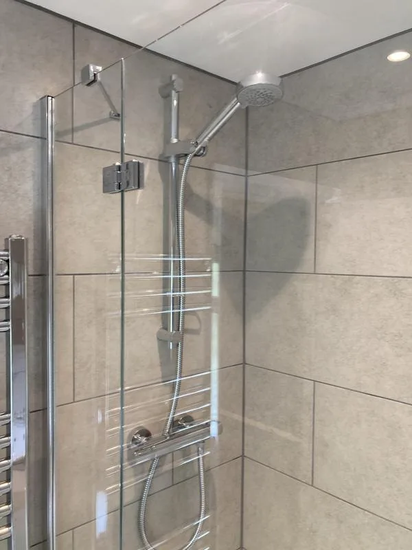 Glass shower screen with thermostatic shower and large-format tiles