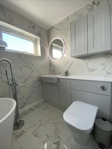 Marble-effect bathroom with illuminated round mirror and fitted units